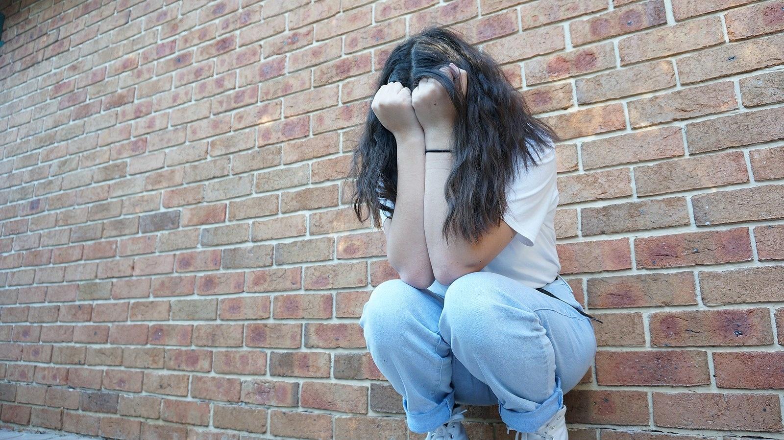 Depressed_girl_by_brick_wall.jpeg